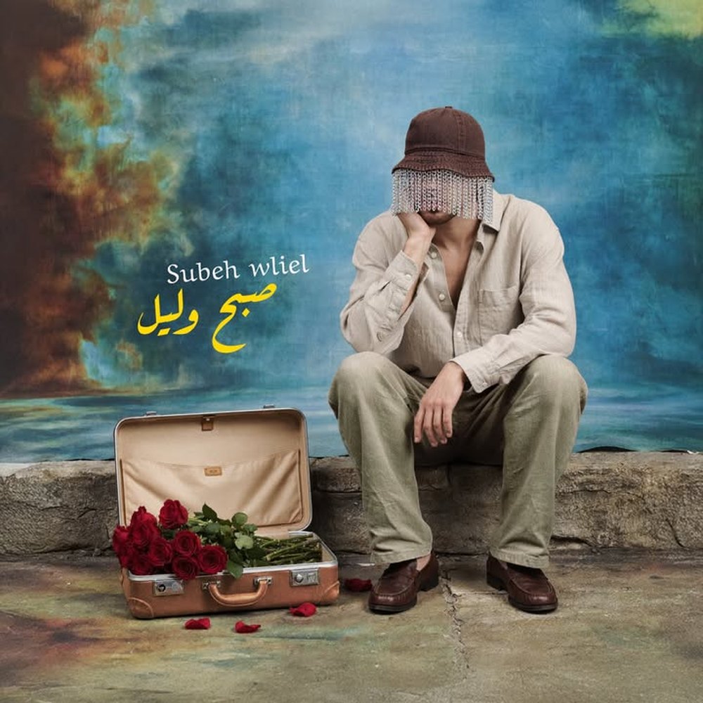 Subeh Wleil cover — a masked figure on a seawall beside a suitcase of red roses.